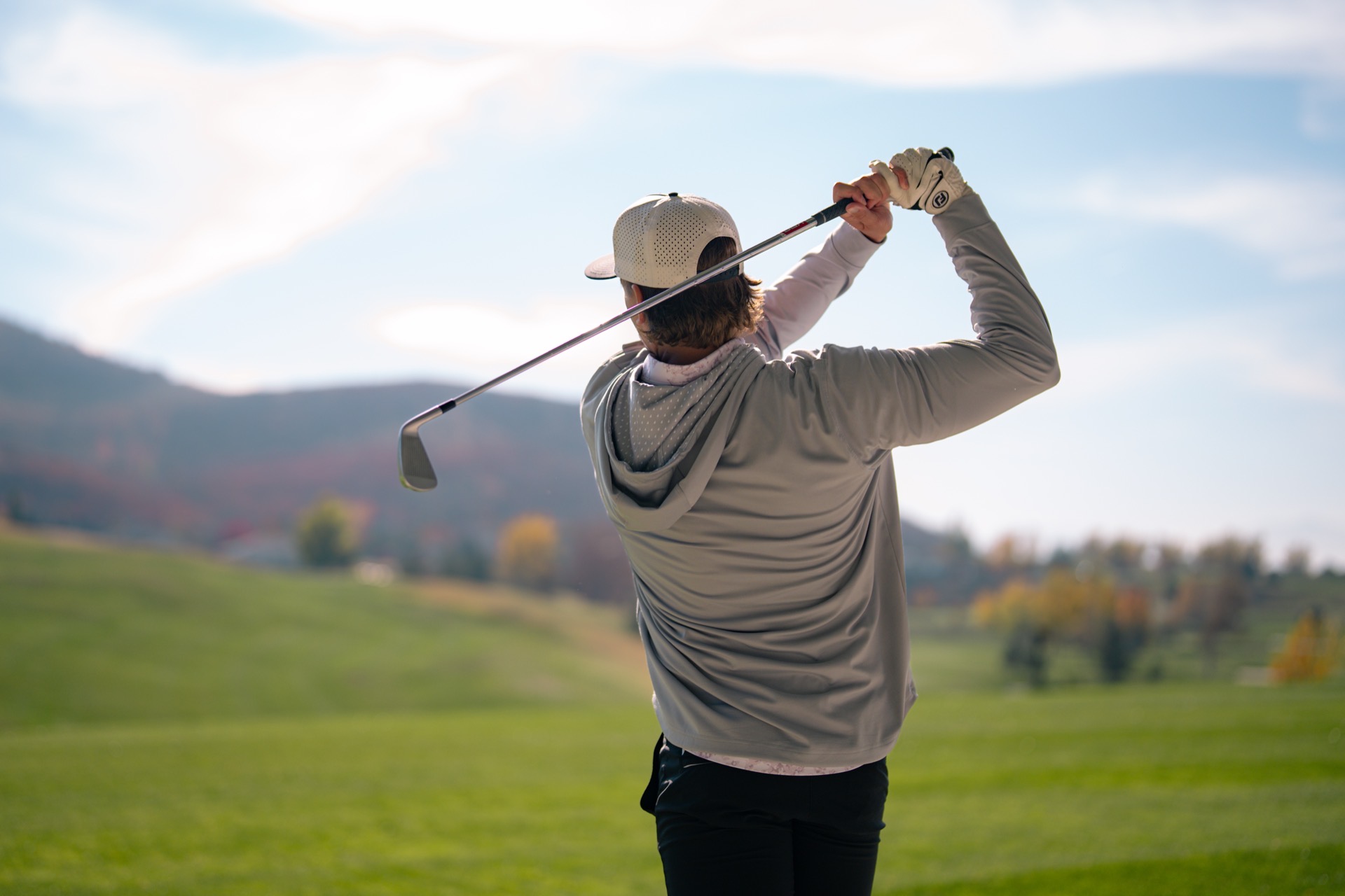 REV Tour player mid-swing with mountain backdrop
