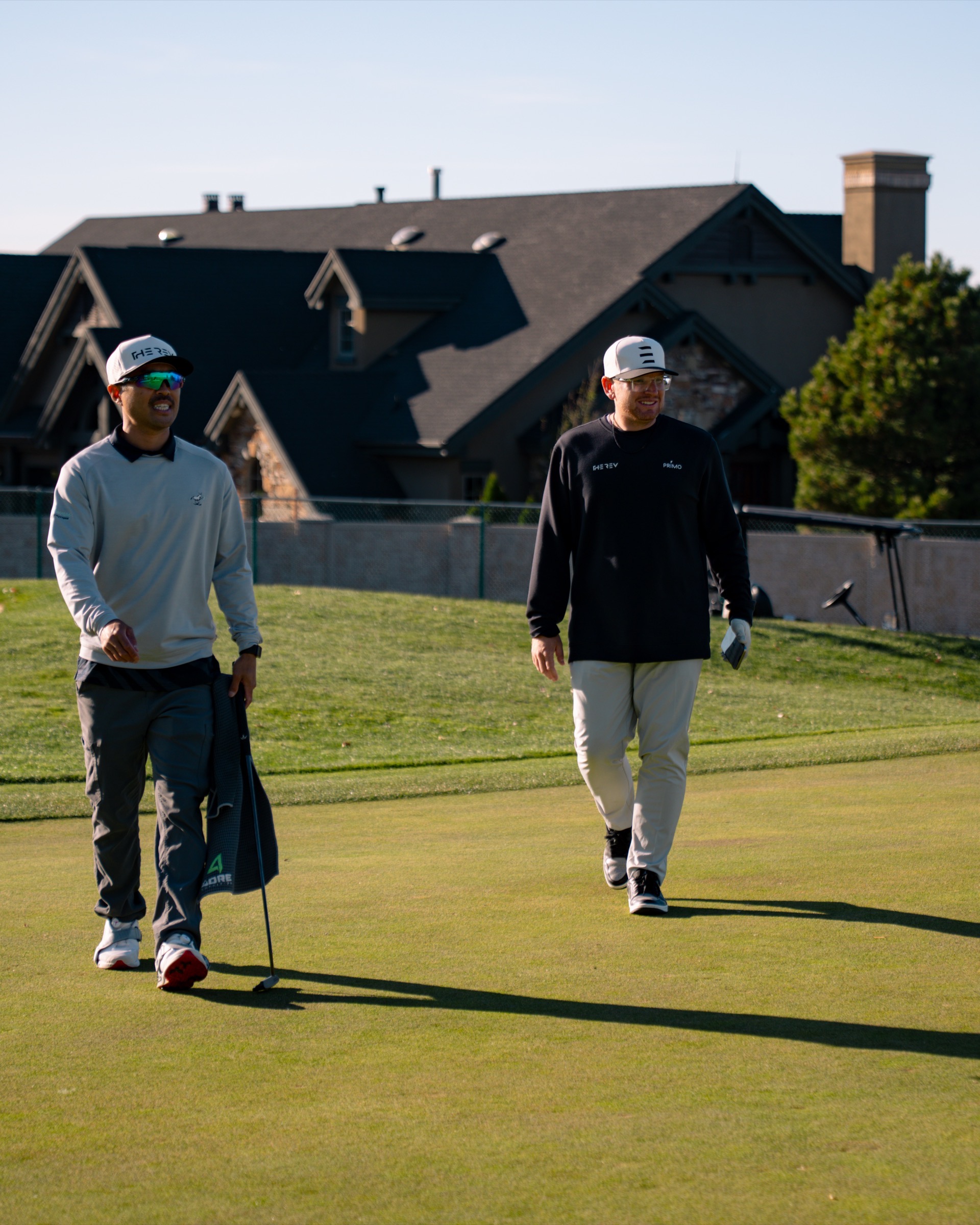 Two REV Tour players walking the fairway with clubhouse behind